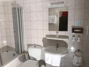 a bathroom with a toilet and a sink and a tub at Hotel Rheinlust in Boppard