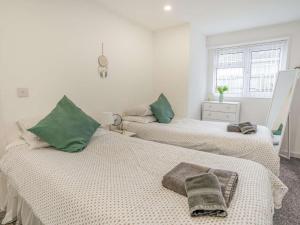 2 Betten mit grünen Kissen in einem weißen Zimmer in der Unterkunft Immaculate 3-Bed 5 berth modernised bungalow! in Tenby