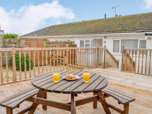 a wooden deck with a table and two glasses of orange juice at Immaculate 3-Bed 5 berth modernised bungalow! in Tenby