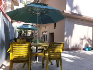 uma mesa com duas cadeiras e um guarda-sol verde em Hotel Quality em Kakarvitta