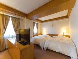 a hotel room with two beds and a flat screen tv at Hotel Matsunoka Ichinoseki in Ichinoseki