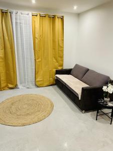 a living room with yellow curtains and a couch at Paname ou Rouen ? in Freneuse
