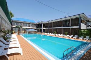 a large swimming pool with white lounge chairs next to a building at Shosh Garden Family Resort in Chorwoq