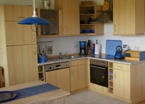una cocina con armarios de madera y fregadero en Ferienwohnung Schwalbennest, en Zudar