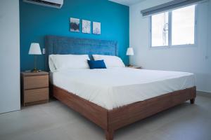 a bedroom with a large bed with a blue wall at Hermosa townhouse boca paraíso in Boca Chica