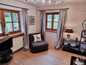 sala de estar con silla y ventanas en Fritzis Alpenidyll „Sommertraum & Winterromantik”, en Samerberg