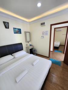 a bedroom with a large white bed and a mirror at LTH (Little Turtle's Home) in Semporna