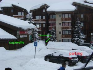 a parking lot covered in snow in front of a building at Au Bord des Pistes in La Plagne