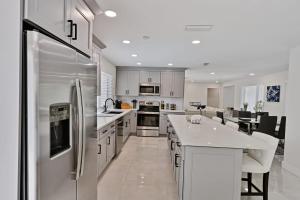 a kitchen with white cabinets and a stainless steel refrigerator at Sail Away Beach Cottage Sleeps 10 Heated Pool in Fort Lauderdale