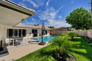 un patio trasero con piscina y valla en Sail Away Beach Cottage Sleeps 10 Heated Pool, en Fort Lauderdale