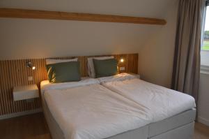 a bedroom with a large white bed with green pillows at Vakantiehuis 't Hertenkamp in Ouddorp