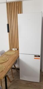 Un refrigerador blanco en una habitación con una mesa. en White Apartment, en Tirana