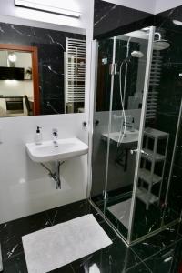 een zwart-witte badkamer met een wastafel en een douche bij Zdrowa Apartment in Wilanów in Warschau