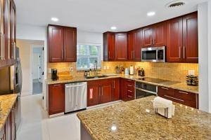 a large kitchen with wooden cabinets and granite counter tops at Moana Beach Cottage in Fort Lauderdale