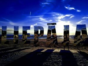 a sign on a beach with the ocean in the background at Ventas in Liepāja +1 photo