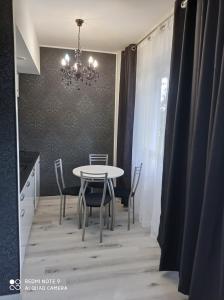 a dining room with a table and chairs and a chandelier at Apartament Lux2 Konin NOCLEGI in Konin