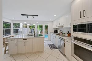 a large kitchen with white cabinets and appliances at Cinderella's Beach Cottage in North Palm Beach