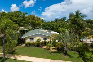 a house with a yard with palm trees at Cinderella's Beach Cottage in North Palm Beach
