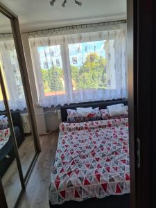 a bedroom with a bed with a red and white quilt at Apartament u Maryśki in Karpacz