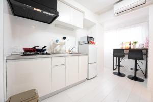 a white kitchen with white cabinets and a counter at GN98 Saiwaicho Osaka in Osaka