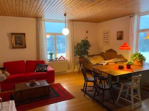 een woonkamer met een rode bank en een tafel bij Mysig lägenhet i Prästgård nära Branäs in Sysslebäck