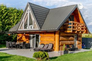 a log cabin with a pitched roof and chairs at Dom na Mazurach WrzoSPA in Stare Juchy