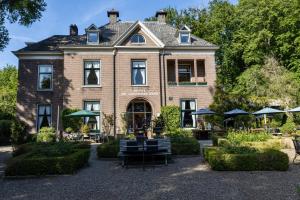 een groot bakstenen huis met een tuin ervoor bij de Lochemse Berg in Barchem