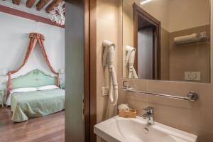 baño con lavabo, espejo y cama en Hotel al Sotoportego en Venecia