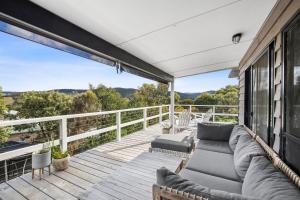 a deck with a couch and chairs on a balcony at Moggs Magic in Aireys Inlet
