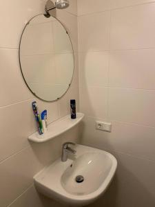 een witte badkamer met een wastafel en een spiegel bij B&B by the C in Vlissingen