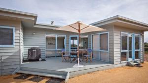 a house with a deck with an umbrella and a table at Moggs View in Aireys Inlet