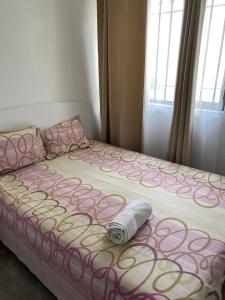 - un lit avec une couette rose et blanche et un rouleau dans l'établissement 2 Bedroom Apartment in Pereybere with Private Balcony, à Pereybere