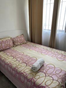 a bed with a pink and white comforter and a roll on it at 2 Bedroom Apartment in Pereybere with Private Balcony in Pereybere
