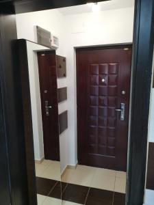 baño con 2 puertas marrones en una habitación en Fun Apartament Militari Residence, en Roşu
