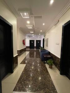 a lobby with a hallway with a blue couch in a building at Al Deyafah Narjis-الضيافة نرجس in Khamis Mushayt