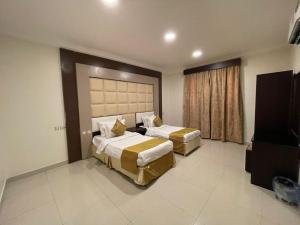 una camera d'albergo con due letti e una televisione di الضيافة ريجنسي - Al Deyafah Regency a Khamis Mushayt