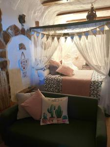 a bedroom with a bed and a couch with curtains at Cuevas de la Paz - Cave House Holidays in Los Carriones