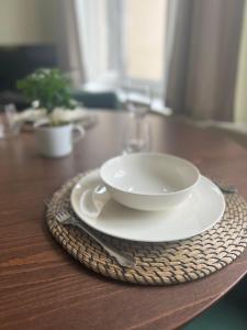 a white bowl on a plate on a wooden table at CityView Apartment in Tallinn