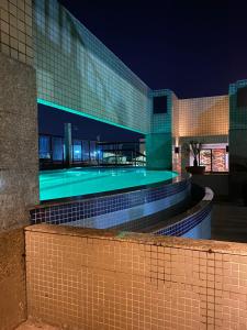 a building with a swimming pool at night at Lindo Flat Particular decorado in Brasilia
