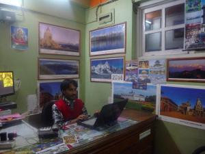 un hombre sentado en un escritorio con un portátil en Pashupati Darshan Hotel en Katmandú