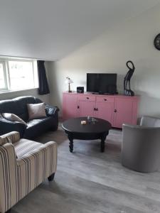 een woonkamer met een zwarte bank en een roze kast bij Gastenverblijf De Handwijzer in Hengelo