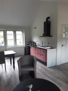 een keuken met roze kasten en een tafel en een stoel bij Gastenverblijf De Handwijzer in Hengelo