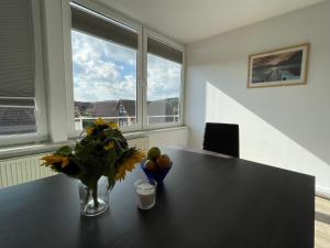 a table with a vase of flowers and fruit on it at Ferienwohnung über den Dächern von Pinnow in Pinnow