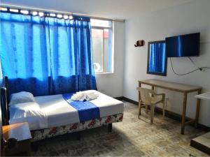 a bedroom with a bed and a desk and a window at Hostal El Rey in Buenaventura