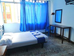 a bedroom with a bed and a desk and a window at Hostal El Rey in Buenaventura