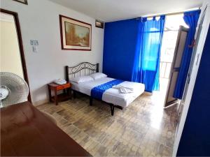 1 dormitorio con 1 cama con pared azul en Hostal El Rey, en Buenaventura