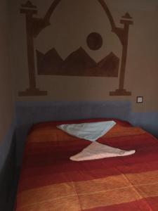 a bedroom with a bed with a blanket on it at Tazoult Ouzina in Ouzina