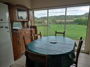 einen Tisch und Stühle in einer Küche mit einem großen Fenster in der Unterkunft Gîte de la Forêt in Saint-Jeanvrin