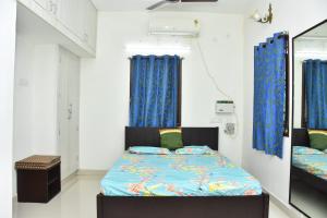 een slaapkamer met een bed met blauwe gordijnen bij Mahabs homestay Villa in Mahabalipuram