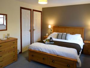 - une chambre avec un grand lit et une tête de lit en bois dans l'établissement Moordale Cottage, à Reeth